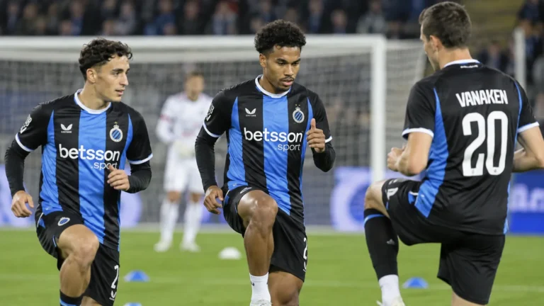 Club Brugge-spelers in blauw-zwarte shirts tijdens een geconcentreerde opwarming op het veld.