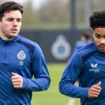 Twee voetballers in blauwe trainingstoppen tijdens een oefensessie op het trainingsveld.
