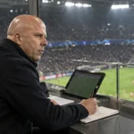 Arne Slot maakt notities vanuit een UEFA-observatiebox in het stadion.