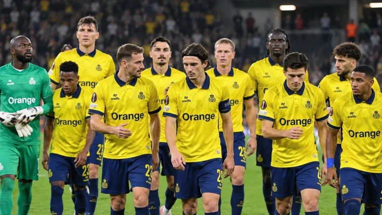 Een groep Union-spelers in gele wedstrijdtenues wandelt samen over het veld na een Europese wedstrijd.