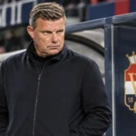 John Stegeman in een neutrale jas bij de technische zone van Willem II.
