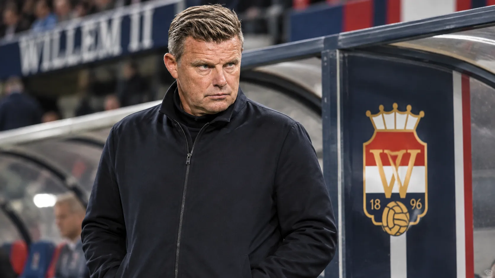 John Stegeman in een neutrale jas bij de technische zone van Willem II.