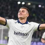 Nicolo Tresoldi juicht op een voetbalveld in een wit shirt met donkerblauwe details.