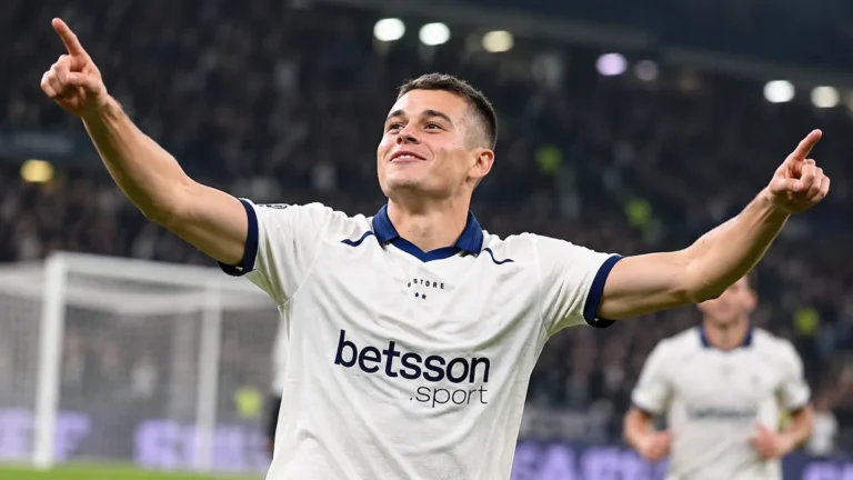 Nicolo Tresoldi juicht op een voetbalveld in een wit shirt met donkerblauwe details.