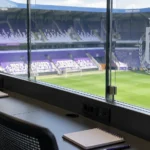 Lege perstafel in een tribuneruimte van RSC Anderlecht met een clubembleem op het glazen paneel.