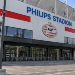 De buitenzijde van het Philips Stadion met een PSV-clubembleem aan de ingang.