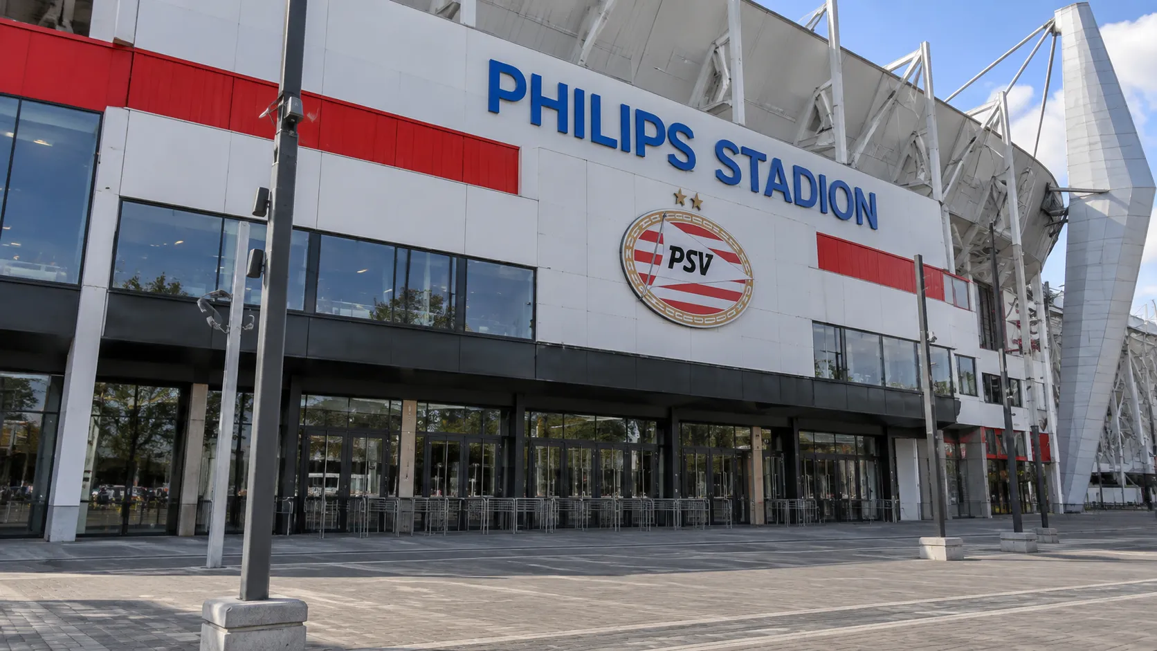 De buitenzijde van het Philips Stadion met een PSV-clubembleem aan de ingang.