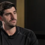 Thibaut Courtois tijdens een rustig media-interview in een ruimte met een subtiel embleem van de Belgische nationale ploeg.