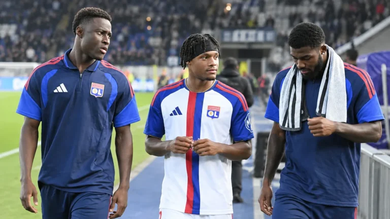 Drie spelers van Olympique Lyonnais lopen naast het veld in hun clubtenue.