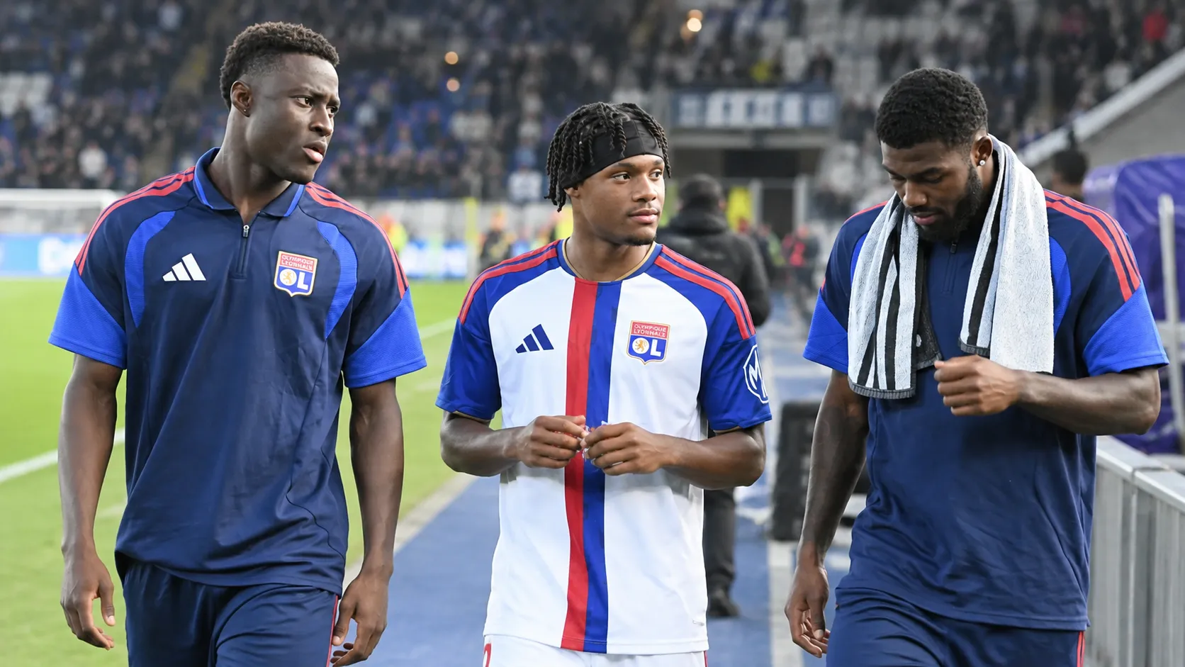 Drie spelers van Olympique Lyonnais lopen naast het veld in hun clubtenue.