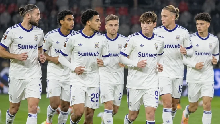 Anderlecht-spelers in witte wedstrijdshirts tijdens de opwarming op het veld.