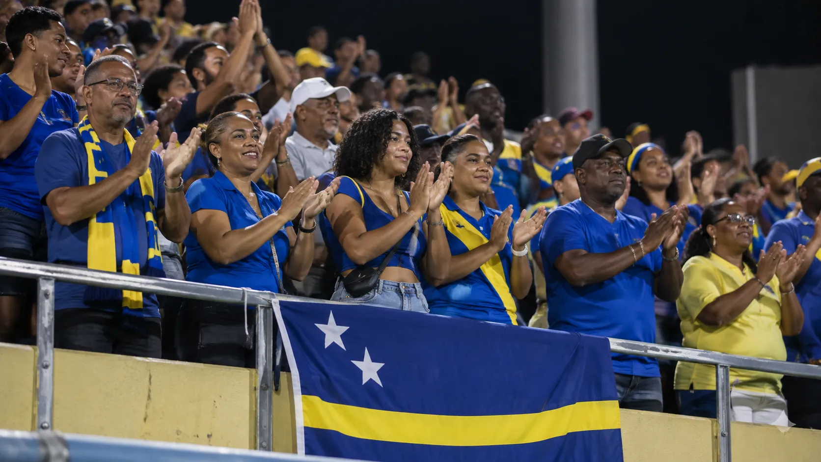 Collectieve supporters van Curaçao met een nationale vlag in de tribunes.