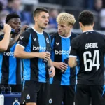 Een groep Club Brugge-spelers drinkt water aan de zijlijn in zwart-blauwe tenues.