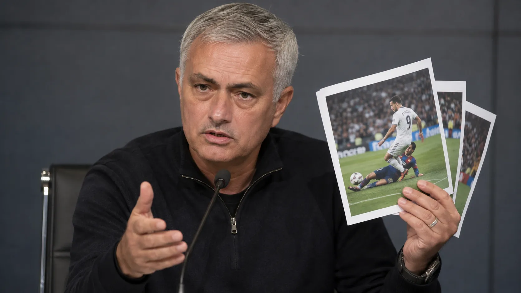 José Mourinho spreekt op een persconferentie terwijl hij afgedrukte wedstrijdfoto’s vasthoudt.