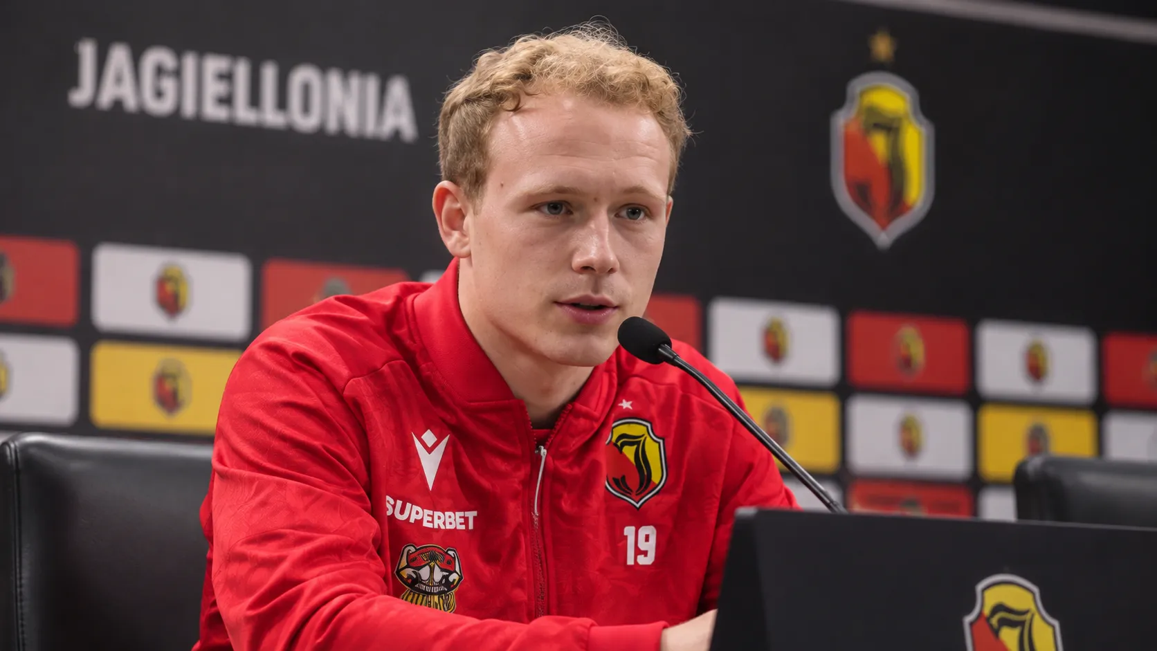 Anders Klynge spreekt op een persconferentie in zijn rode Jagiellonia-trainingsjas.