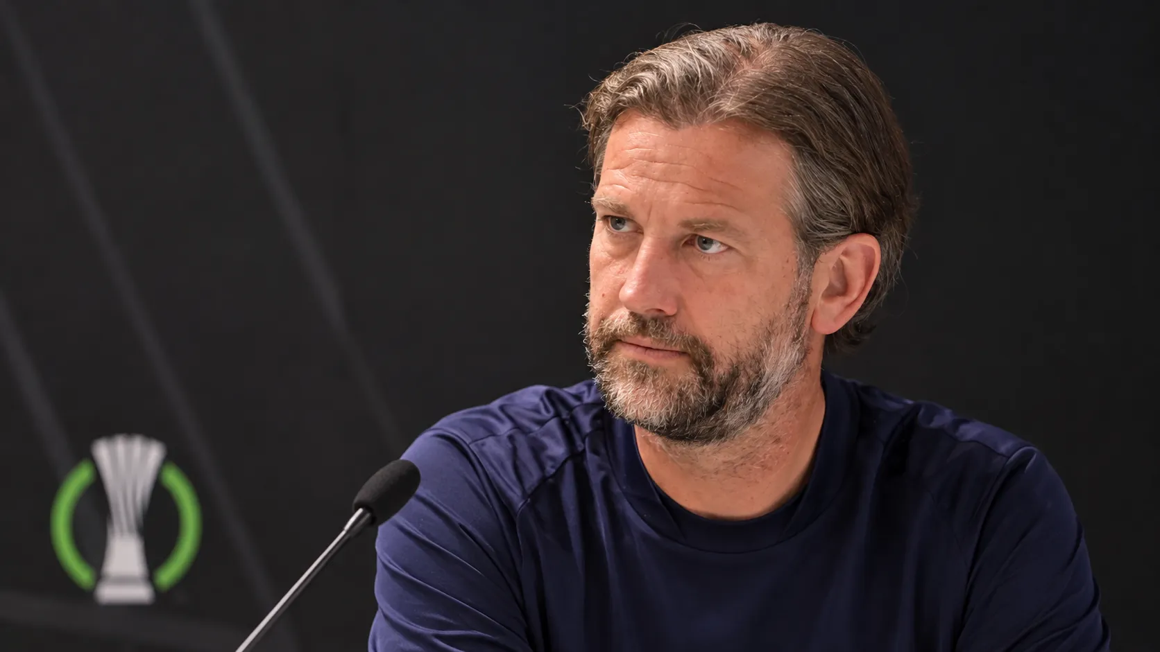 Rik De Mil in een KAA Gent-trainingsshirt tijdens een gesprek met de media.