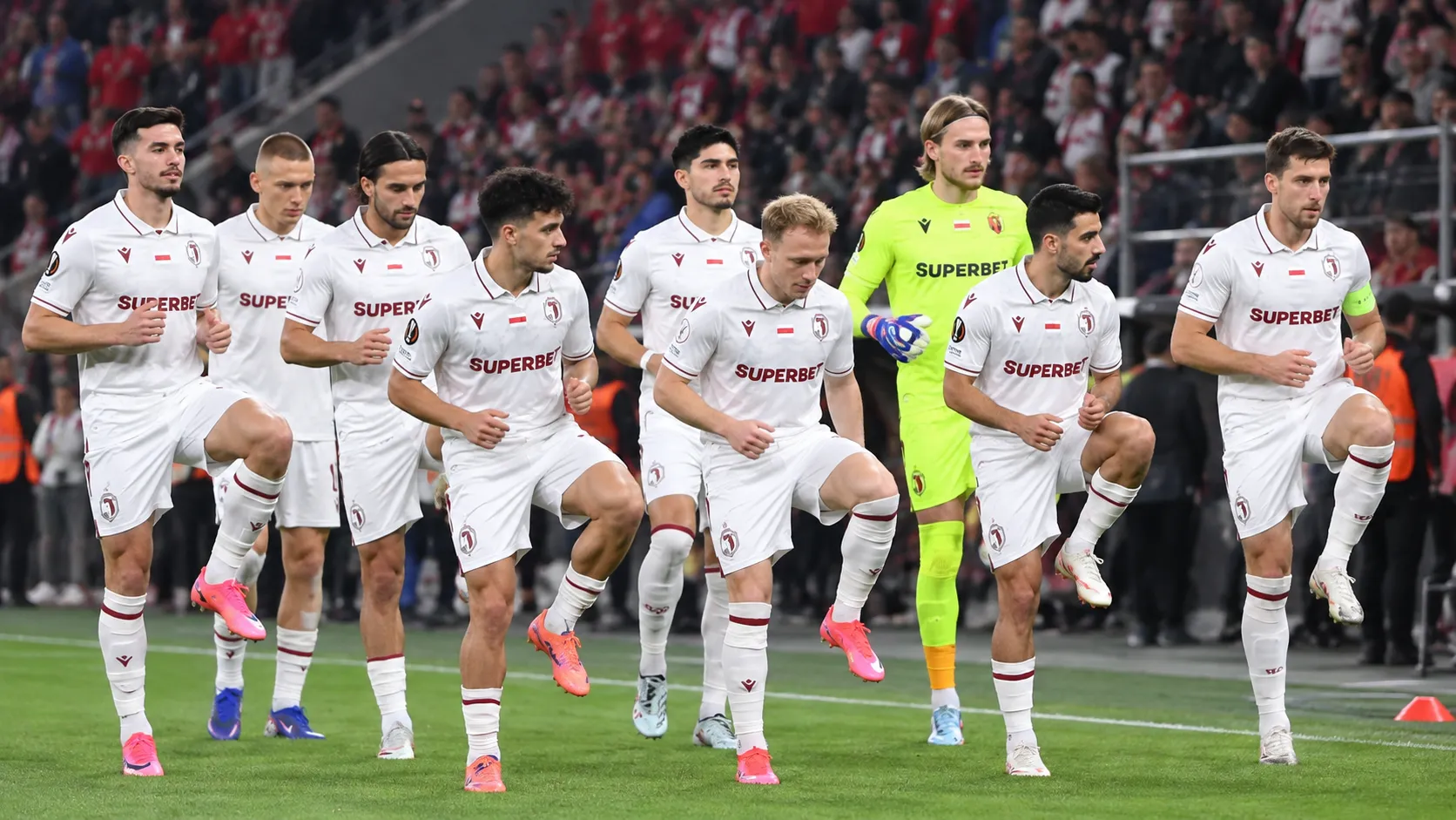 Een groep voetballers in witte wedstrijdshirts op het veld tijdens een nieuw pre-matchmoment.