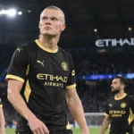 Erling Haaland in het zwarte en gele shirt van Manchester City in een verlicht stadion.