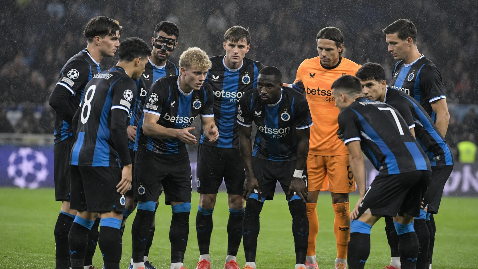 Club Brugge-spelers verzamelen zich in de regen op het veld voor de tweede helft.