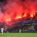Bezoekerssupporters steken fakkels af in een rokerig stadionvak tijdens Club Brugge tegen RC Lens.