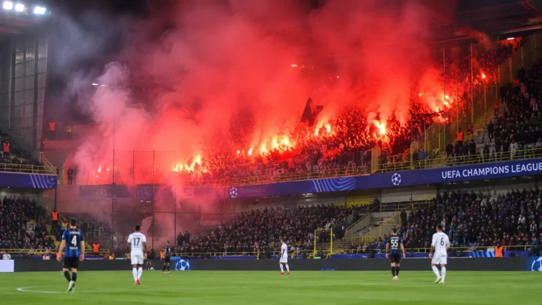 Bezoekerssupporters steken fakkels af in een rokerig stadionvak tijdens Club Brugge tegen RC Lens.