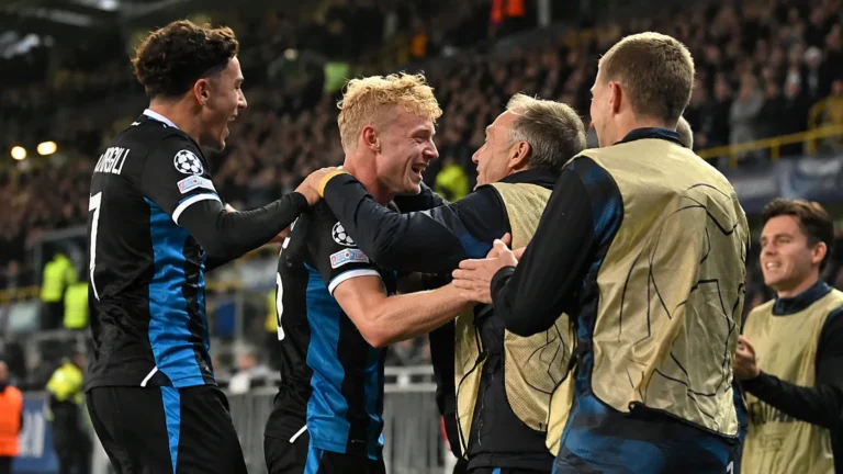 Spelers en staf van Club Brugge vieren samen naast het veld.