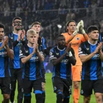 Spelers van Club Brugge applaudisseren na afloop op een regenachtig veld.