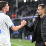 Een Club Brugge-speler en een niet-spelende clubmedewerker wisselen na de wedstrijd een handgebaar uit langs het veld.