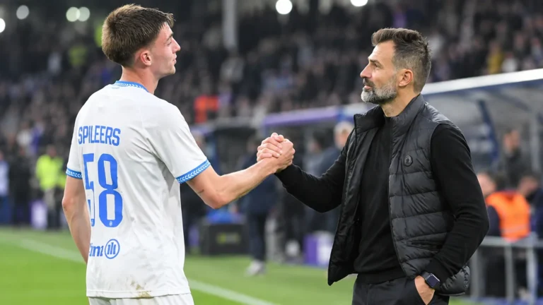 Een Club Brugge-speler en een niet-spelende clubmedewerker wisselen na de wedstrijd een handgebaar uit langs het veld.