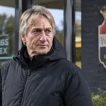 Adrie Koster in een neutrale jas aan de ingang van het trainingscomplex van Willem II.