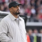 Vincent Kompany kijkt rustig toe aan de rand van een voetbalstadion.