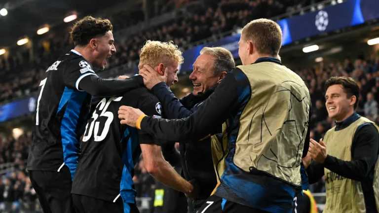 Spelers en stafleden van Club Brugge vieren samen aan de zijlijn van een avondwedstrijd.