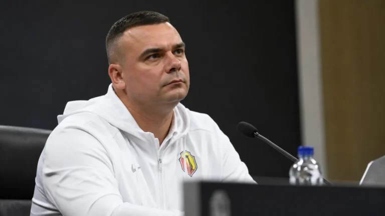 Adrian Siemieniec in een witte sporttrui tijdens een persmoment voor de wedstrijd.