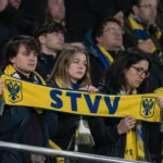 Een groep STVV-supporters met sjaals op een stadiontribune.