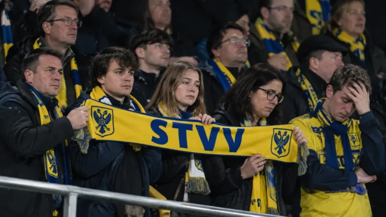Een groep STVV-supporters met sjaals op een stadiontribune.