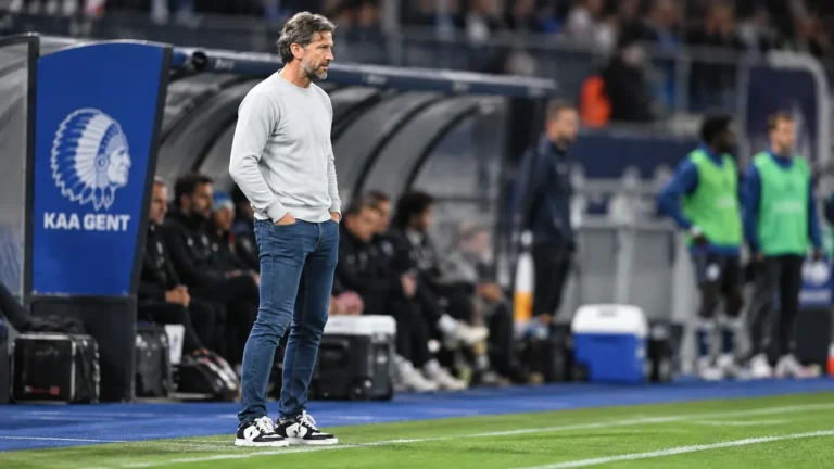 Rik De Mil staat in de technische zone langs het veld bij een wedstrijd van KAA Gent.