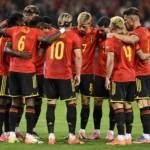 Een groep Belgische internationals vormt in rode wedstrijdshirts een hechte kring op het veld.
