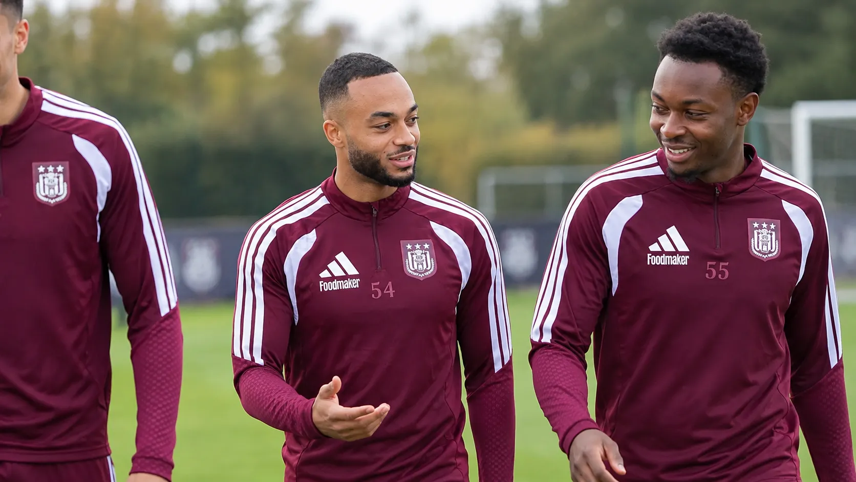 Een groep Anderlecht-spelers in bordeaux trainingskleding tijdens een training op een buitenveld.