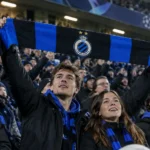 Een groep Club Brugge-supporters houdt in het stadion een blauw-zwarte sjaal omhoog.
