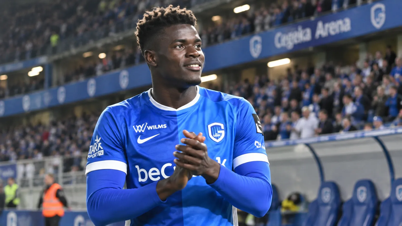 Aaron Bibout in het blauwe shirt van KRC Genk aan de rand van het veld.