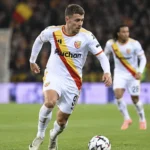 Thorgan Hazard in een wit wedstrijdshirt op een verlicht voetbalveld.