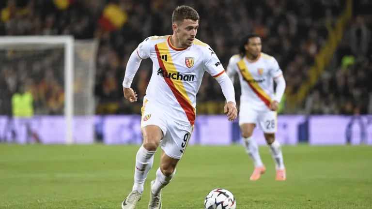 Thorgan Hazard in een wit wedstrijdshirt op een verlicht voetbalveld.