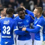 Spelers van KRC Genk vieren samen een doelpunt op het veld.