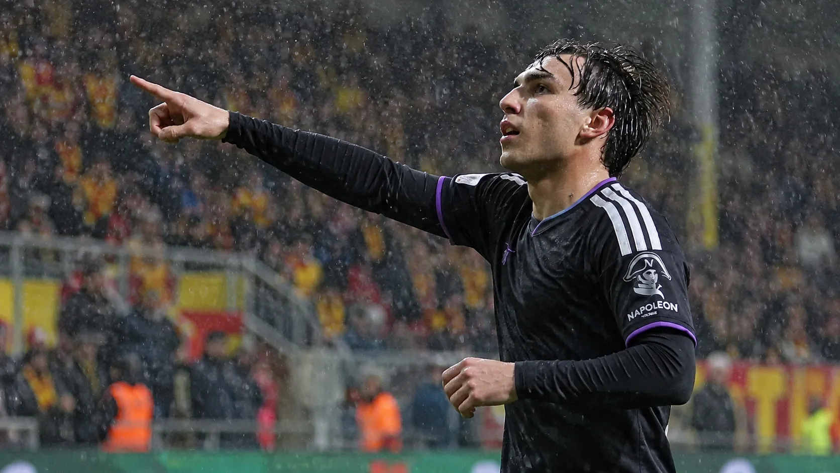 Een Anderlecht-speler viert tijdens een regenachtige Europese wedstrijd.