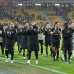 Een groep Anderlecht-spelers applaudisseert na afloop op het veld van een Europees stadion.