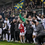 Spelers en staf vieren samen een Europese uitzege aan de rand van het veld.