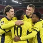 Een groep Union SG-spelers in gele wedstrijdshirts viert samen in een vrijwel leeg stadion.