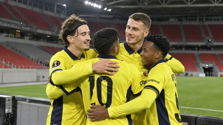 Een groep Union SG-spelers in gele wedstrijdshirts viert samen in een vrijwel leeg stadion.