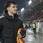 Een Anderlecht-speler in een donkere jas langs de zijlijn na een wedstrijd.