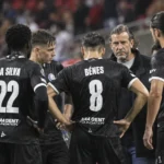 Spelers van KAA Gent verzamelen zich na de wedstrijd rond een staflid langs de zijlijn.